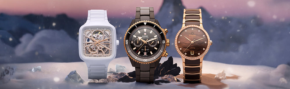 Three Rado watches displayed on a snowy holiday-themed background: a white skeleton dial watch on the left, a black ceramic chronograph watch in the center, and a rose gold and black ceramic watch with diamond accents on the right